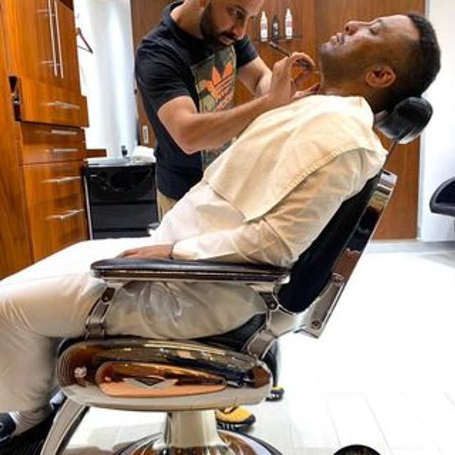 Barber grooming a client at Hair Beats Gents Salon